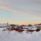 Mehamn i Finnmark med røde hus, kirke og snødekt landskap i mykt vinterlys ved fjorden