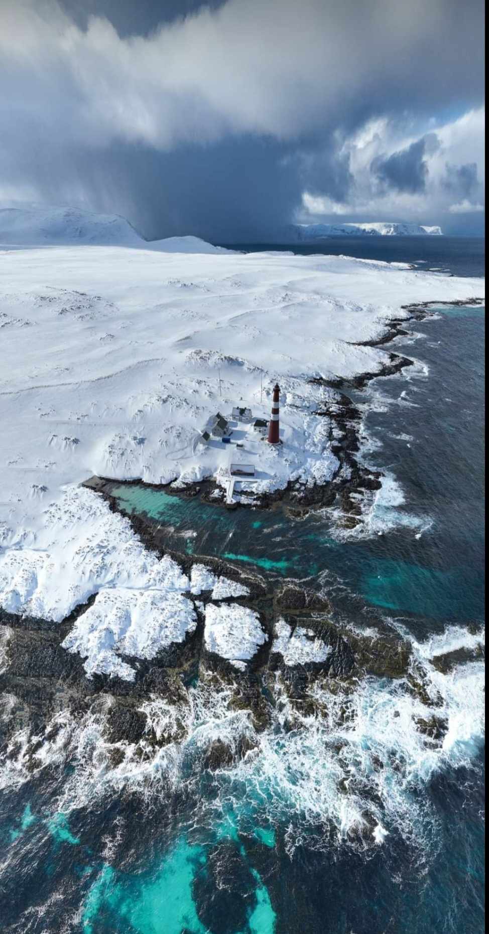 Slettnes fyr i Finnmark med snødekt kyst og hav sett ovenfra, fotografi av Nikolay Kutuzov