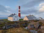 Slettnes fyr i Finnmark med hus og kystlandskap i høstlys og lav sol over havet
