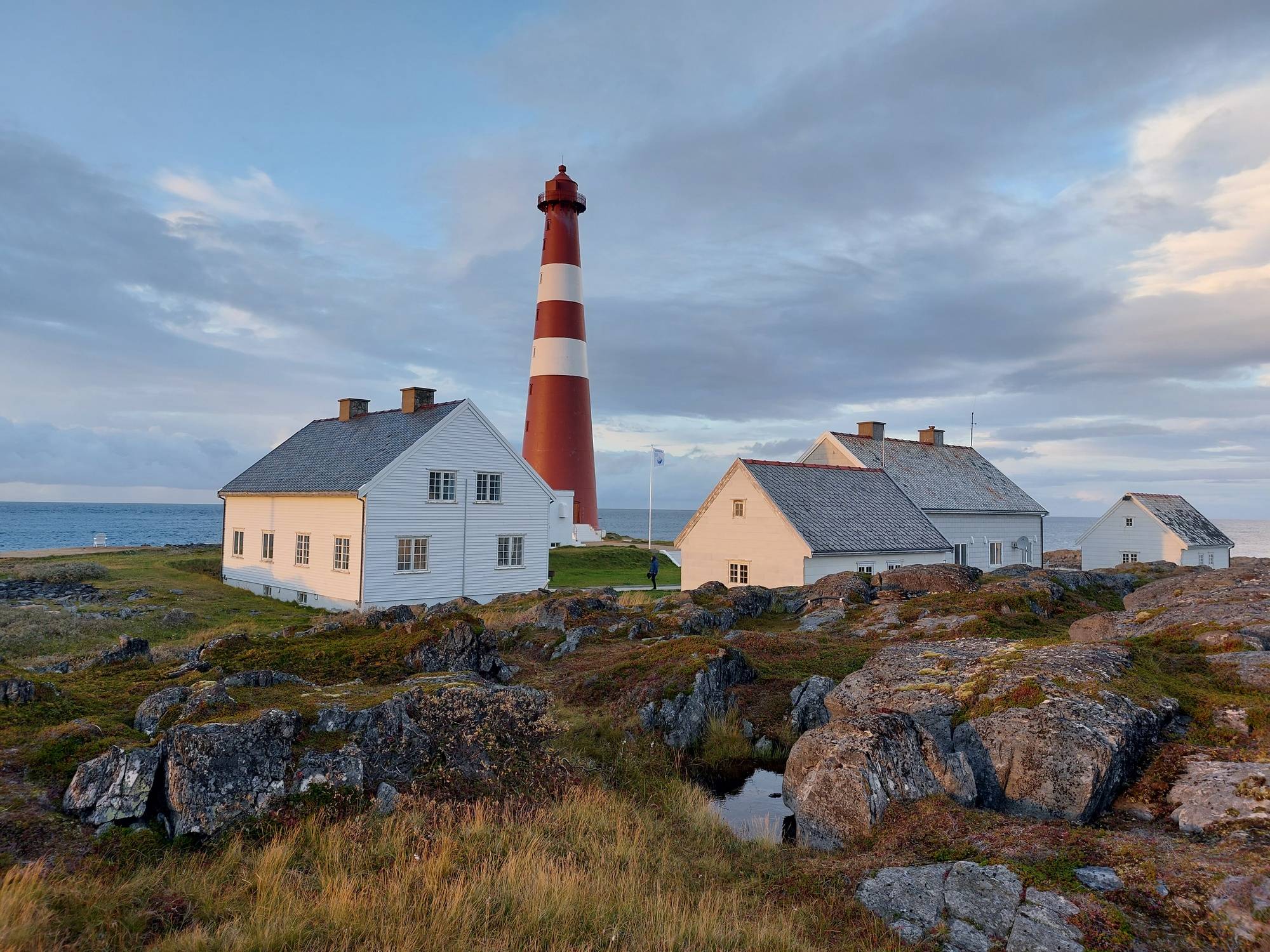 Slettnes fyr i Finnmark med hus og kystlandskap i høstlys og lav sol over havet