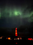 Slettnes fyr i Finnmark med nordlys over himmelen og fyrtårn i vintermørket
