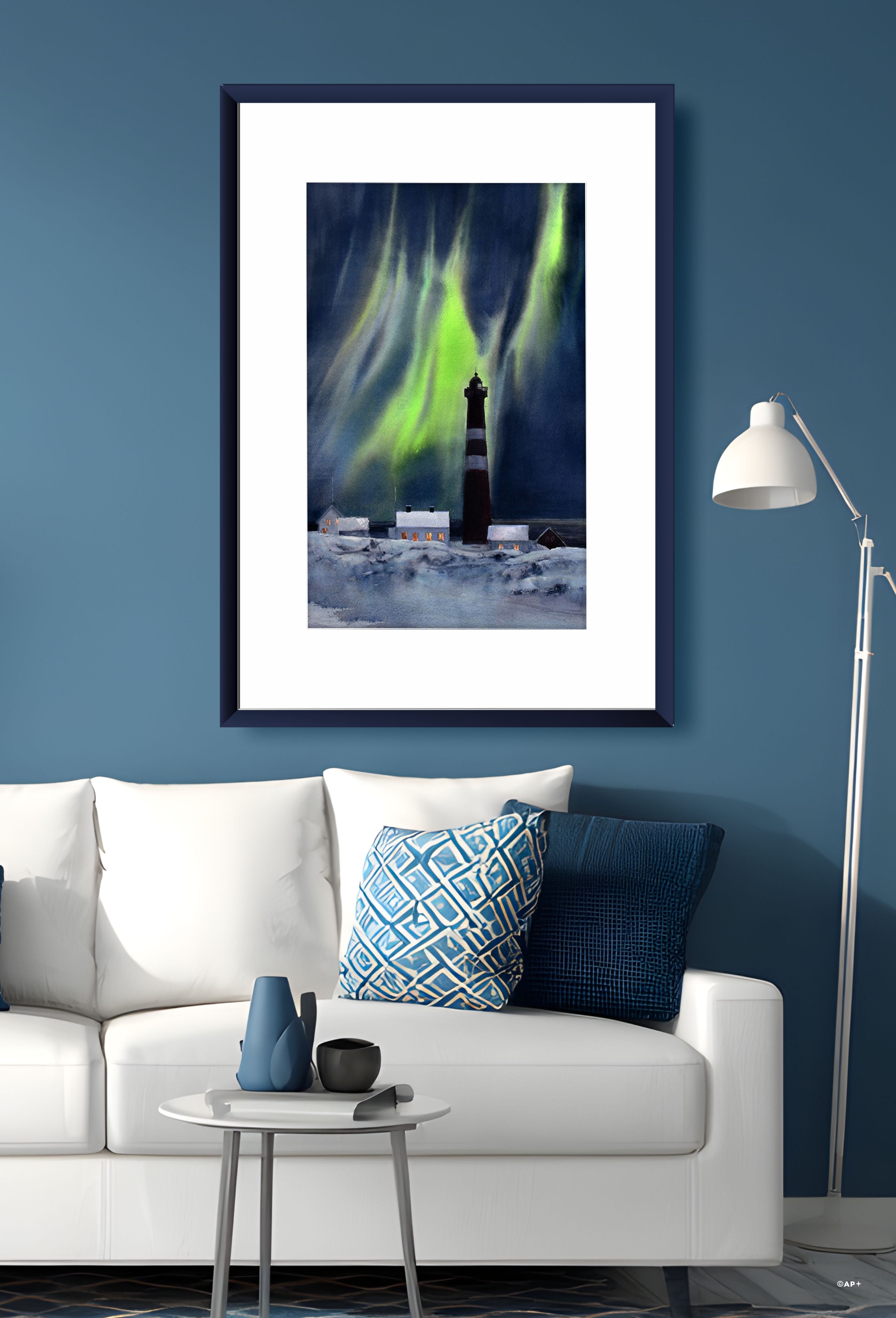 Akvarell av Slettnes fyr under nordlys med snødekt landskap og lys i husene, vist i ramme på vegg