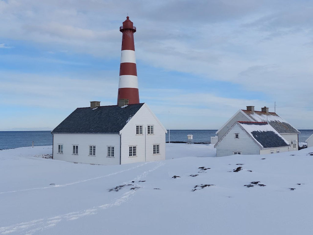 Slettnes fyr i Finnmark med hvite hus og snødekt landskap ved kysten om vinteren